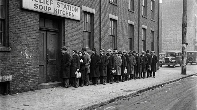 Historical black and white photograph of people waiting in line outside a relief station during the Great Depression